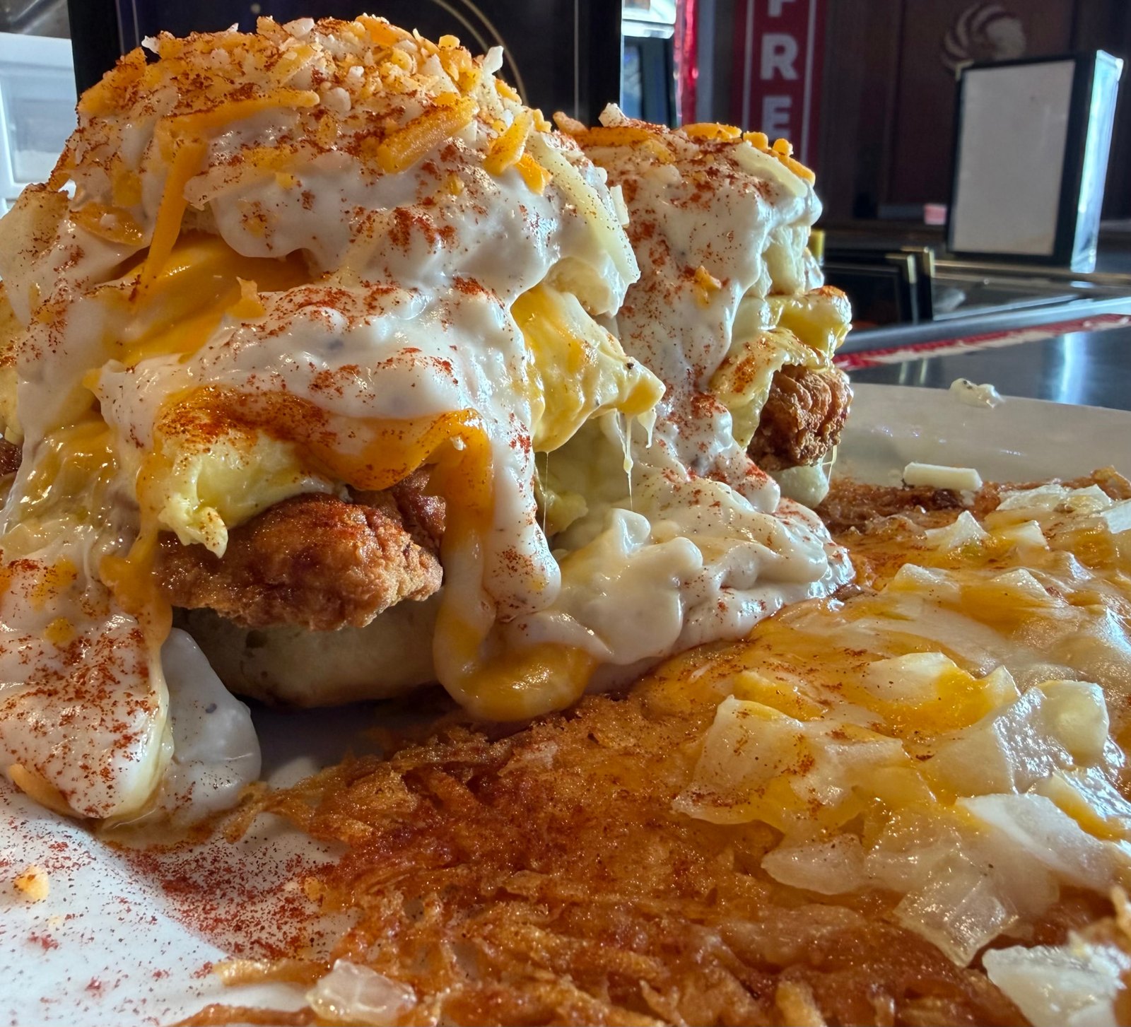 Country fried chicken and eggs stacked on a biscuit with gravy