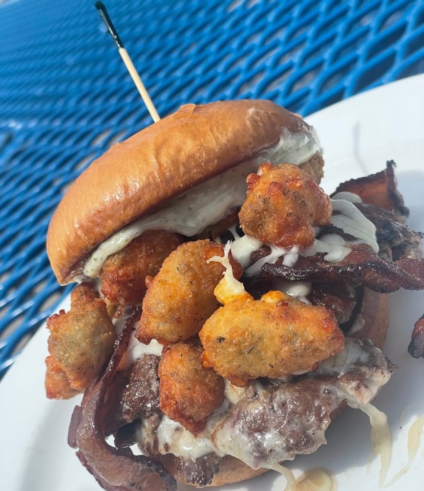 Stacked smash burger with bacon and crispy tots on a brioche bun